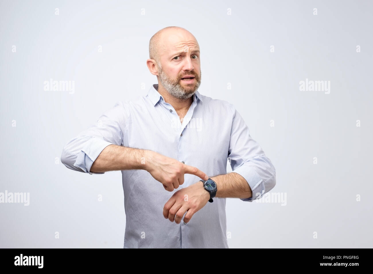 Mature european businessman impatiently pointing to his watch. Why are you late concept. I am waiting here for hours. Stock Photo