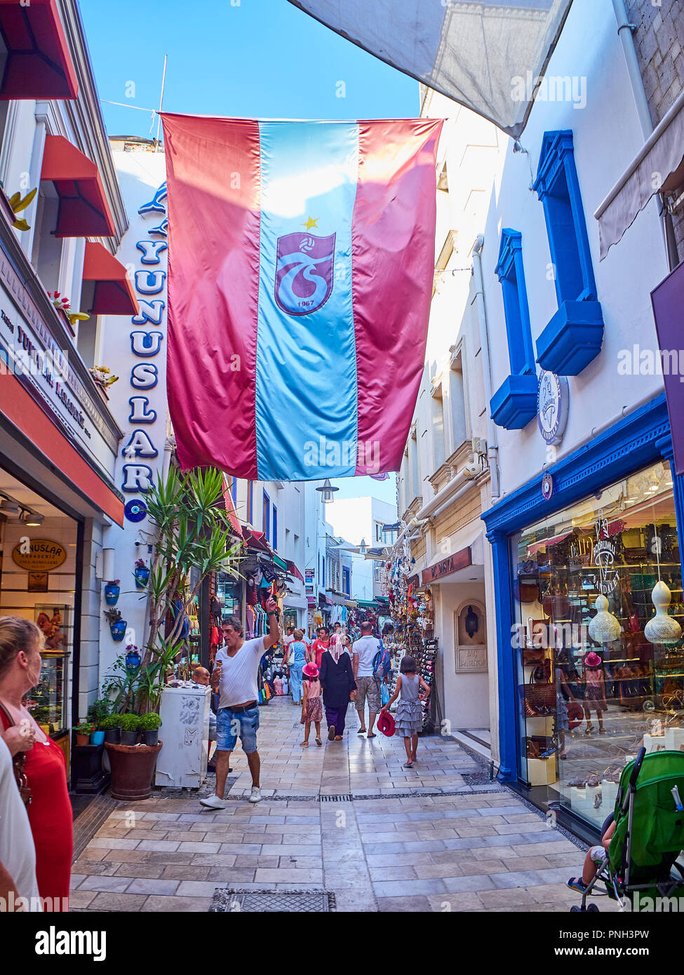 Bodrum, Turkey - July 5, 2018. A man pointing to the flag of Turkish football club Trabzonspor in a street of Bodrum downtown. Mugla Province, Turkey. Stock Photo