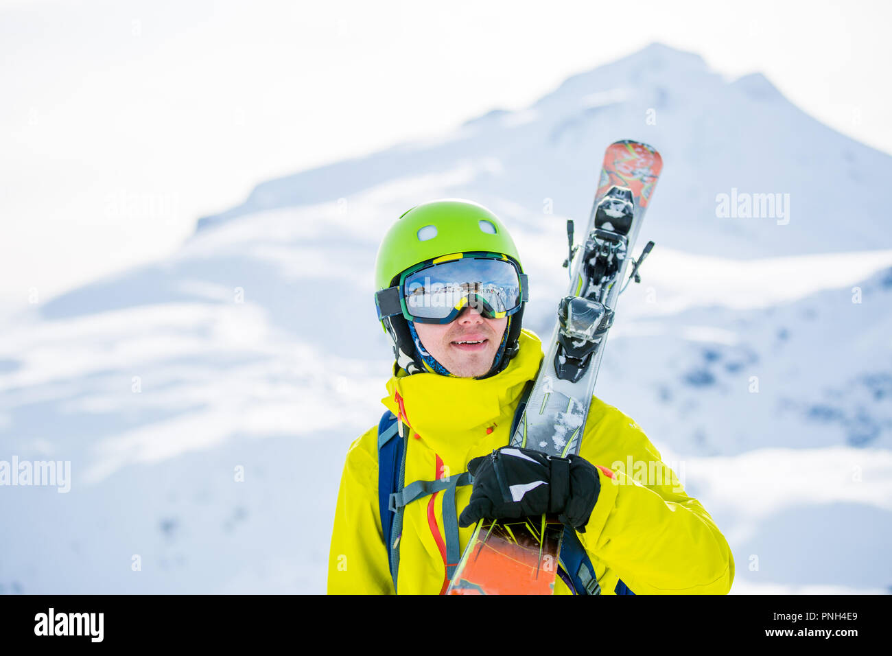 Photo of man wearing helmet wearing glasses with skis Stock Photo