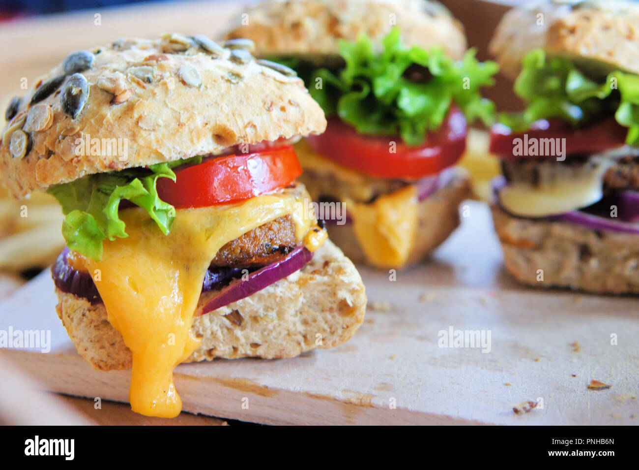 Several small cheeseburger sliders made from worm burger patties. The insect burgers are made from buffalo worms, which are the larvae of the darkling Stock Photo