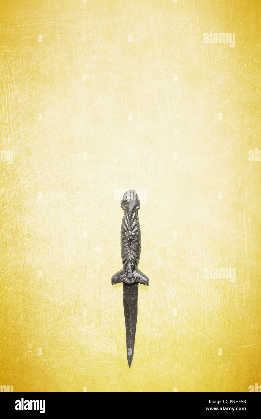 Black wicca wiccan dagger on a textured yellow background.  Ceremonial blade for use in religious and spiritual rituals. Stock Photo