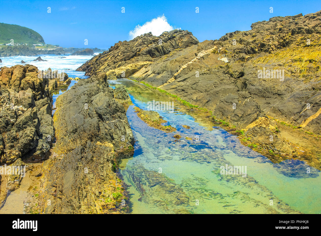 Rocks, tide pools and crashing waves in Tsitsikamma Nature Reserve on Garden Route in South Africa. The natural pools of the Storms River are a popular attraction in the Eastern Cape.Blu sky in summer Stock Photo