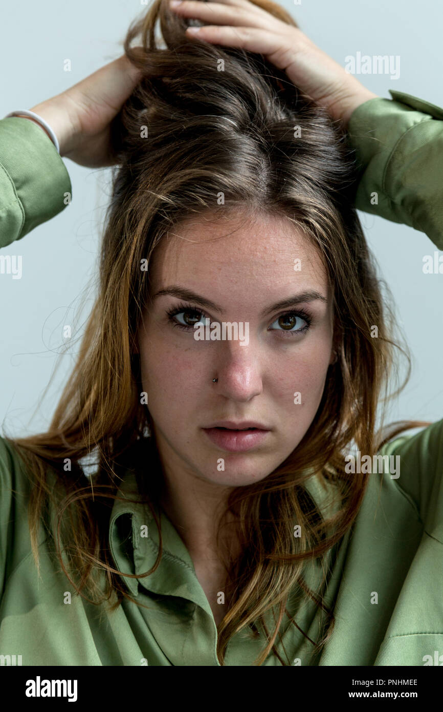 Close up of a young woman with hands on hair. Looking at camera. Stock Photo