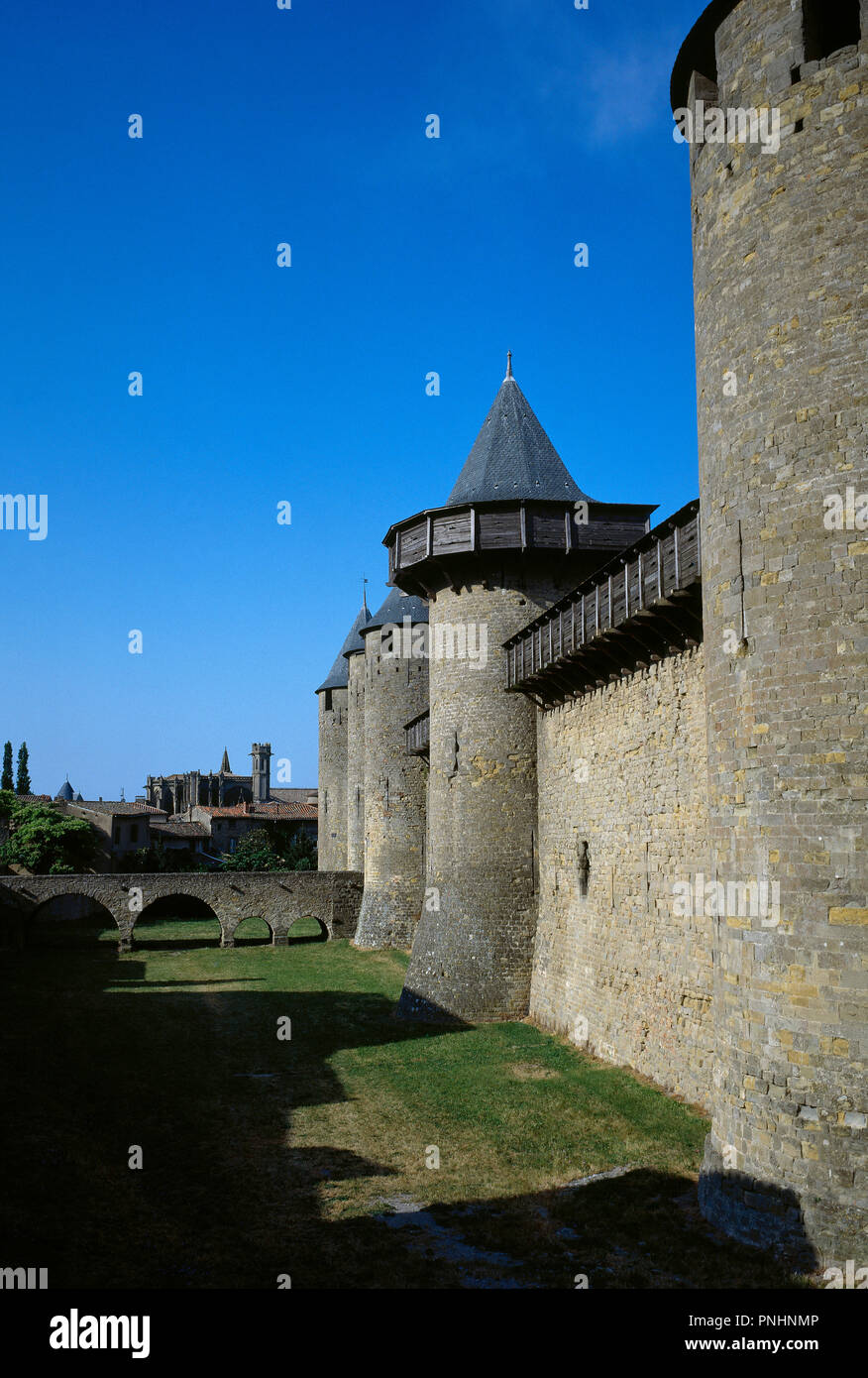 France. Aude department. Occitanie region. Cite de Carcassonne. Medieval citadel. The architect Eugène Viollet-le-Duc renovated the fortress (1853-1879). Defensive towers of the Condal castle, residence of the Trencavell (12 th century). The king Jaime I, in his childhood, was imprisoned in this castle by order of the Lord of Montfort. In the background the Basilica of Saints Nazarius and Celsus. Stock Photo