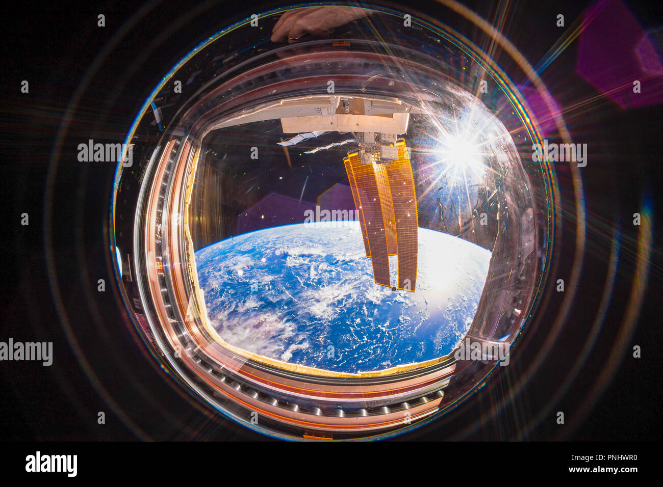 The beautiful planet Earth is seen from inside the International Space Station (ISS). Wide angle view with the sun in the image. Stock Photo