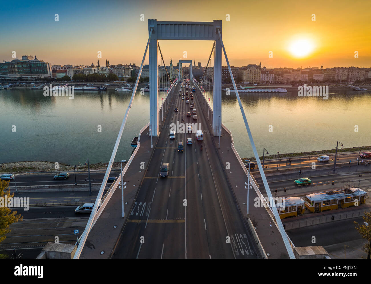 Budapest, Hungary - Beautiful Elisabeth Bridge (Erzsebet hid) at sunrise with golden and blue sky, traditional yellow tram and heavy morning traffic Stock Photo