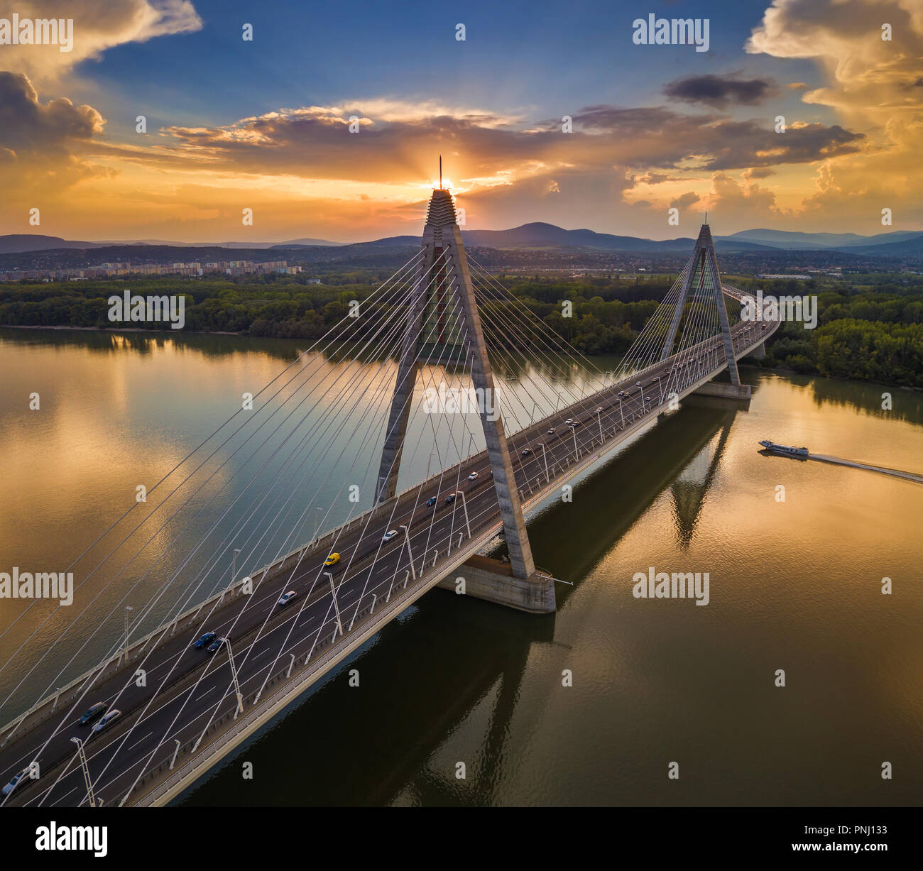Budapest, Hungary - Megyeri Bridge at sunset with speedboat on River Danube and heavy traffic and beautiful blue & orange sky Stock Photo