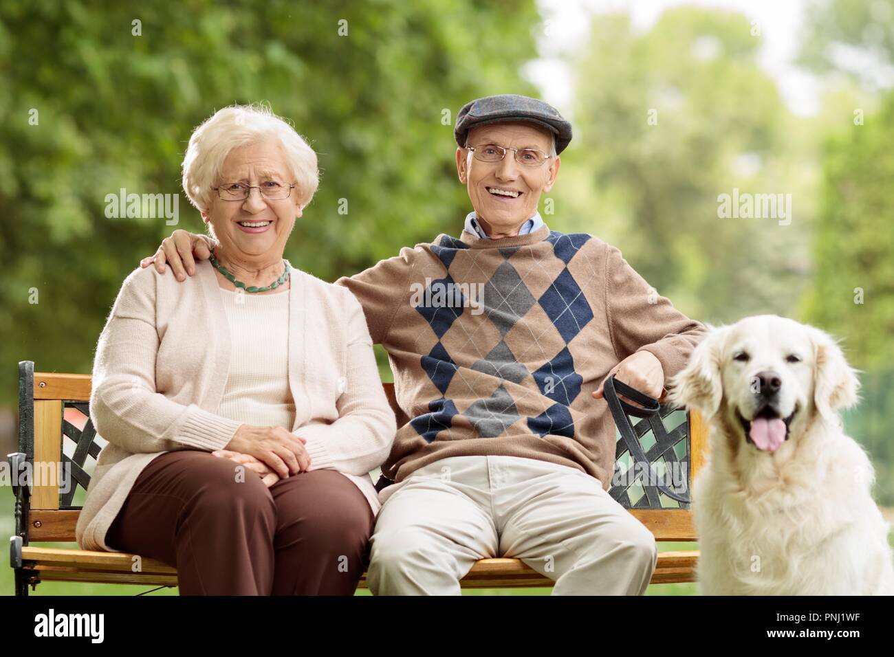 Senior couple with a dog sitting on a bench outdoors Stock Photo - Alamy