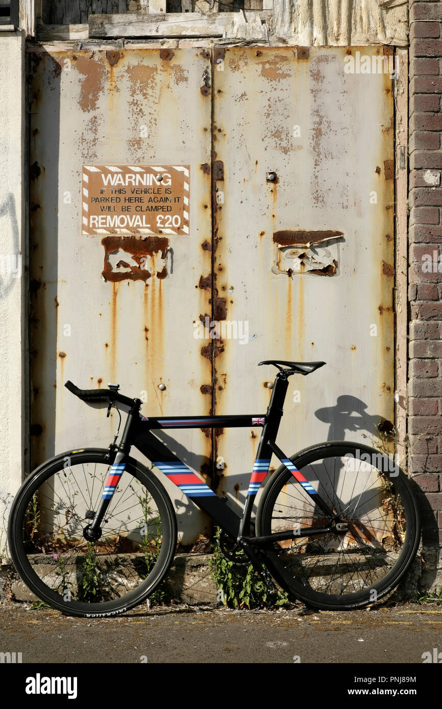 Fixed wheel bicycle in front of abandoned industrial building, Grimsby, UK. Stock Photo
