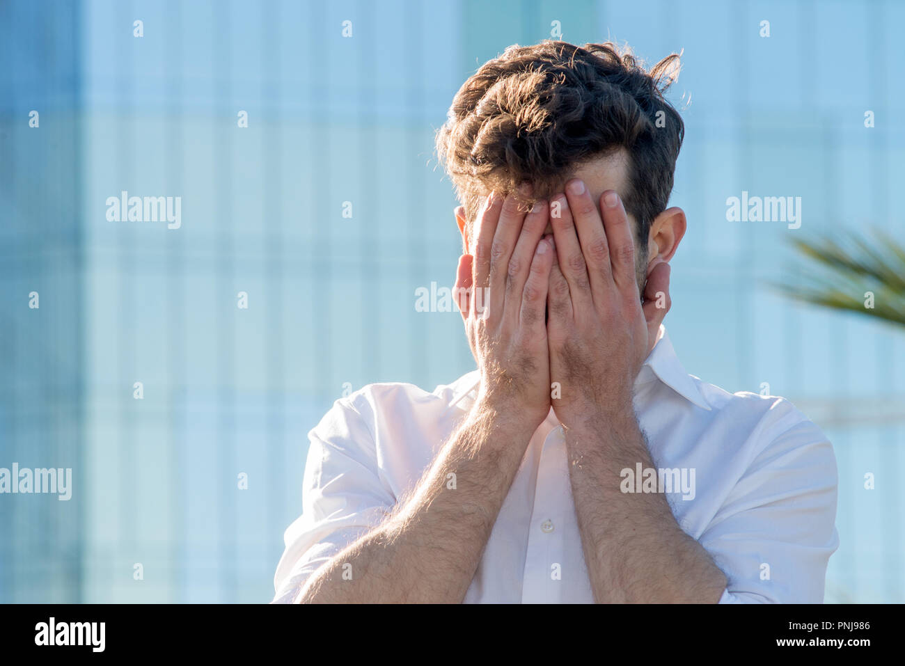 Young Man covered his face with his hands Stock Photo - Alamy