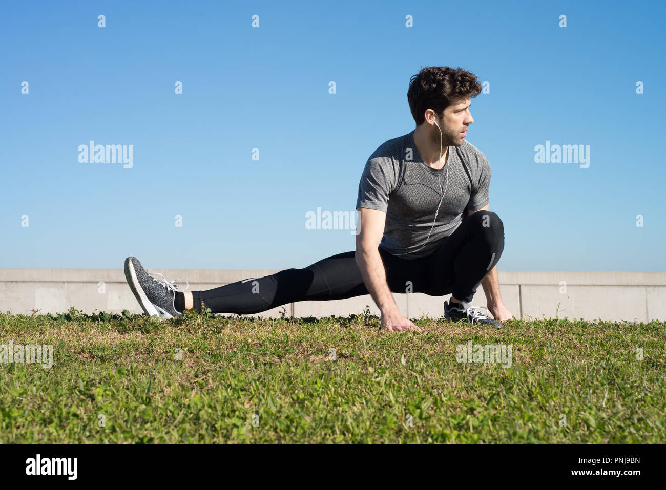man stretches leg in the ground in the grass Stock Photo