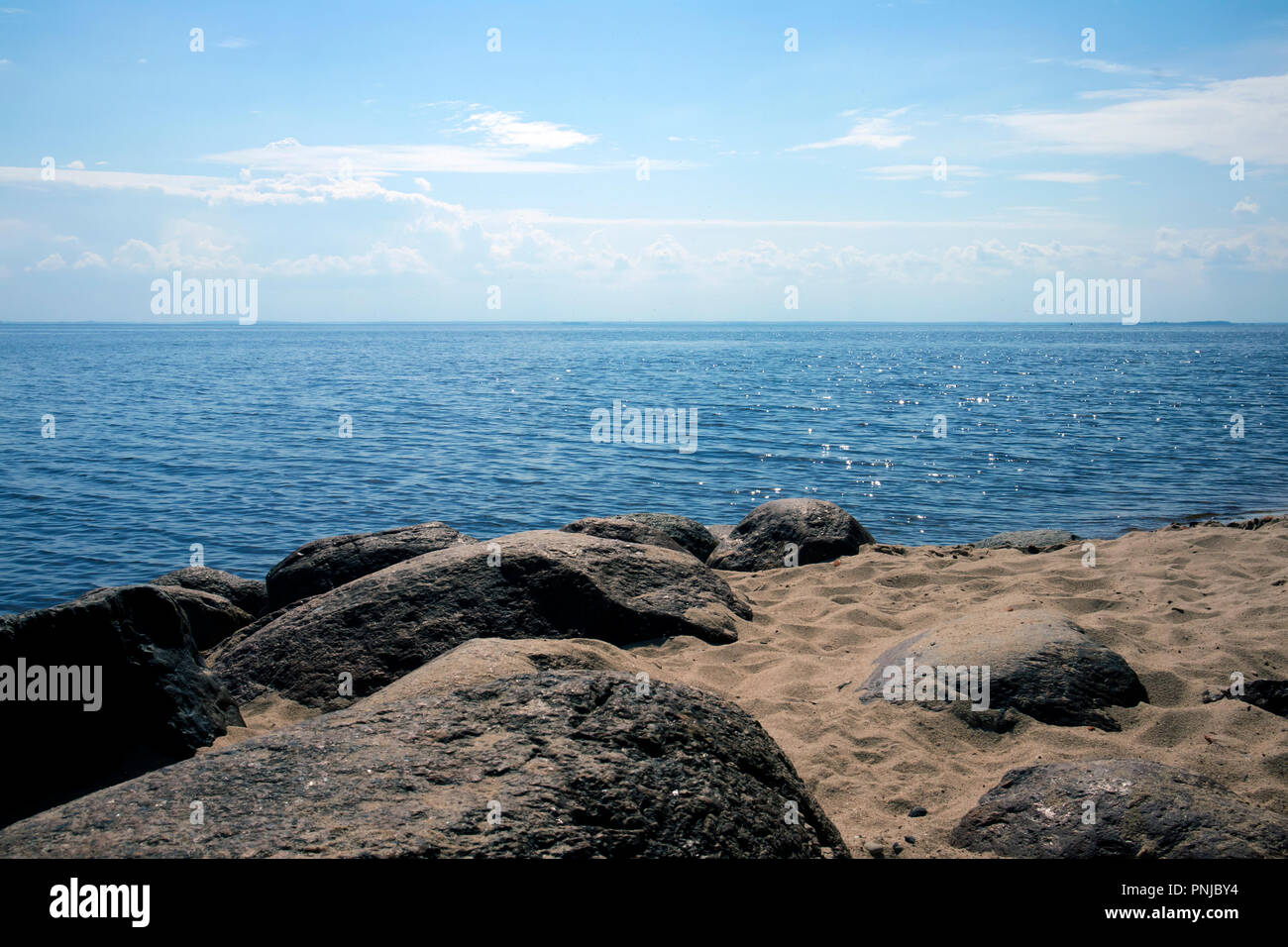 Picturesque landscape with sandy shore, boulders, sea and sky, atmospheric view Stock Photo