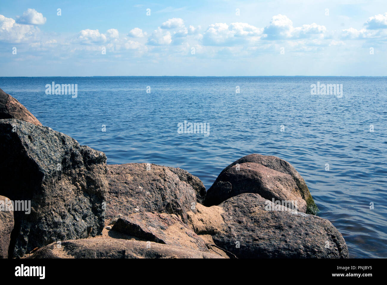 Scenic landscape with sandy shore, boulders, sea and sky, atmospheric view Stock Photo