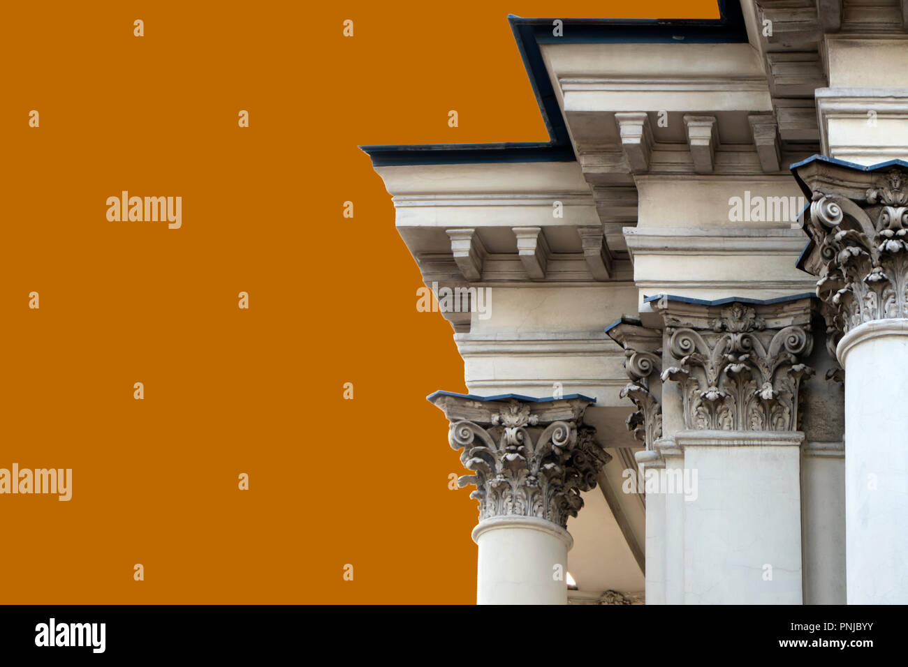 Cornice and ornate columns tops of old building of 19th century in classic style isolated on orange background Stock Photo