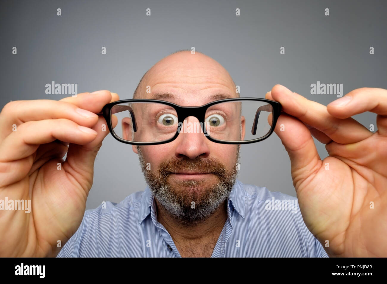 Funny european man looking through glasses. Have problems with eyesight. His eyes are looking very small Stock Photo