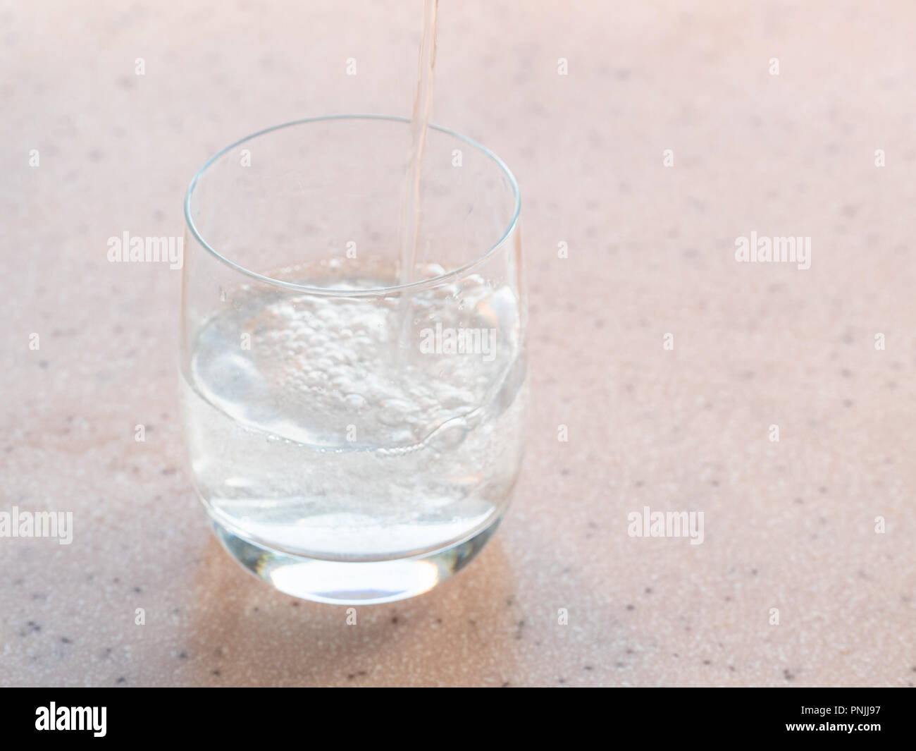 sparkling mineral water fills a glass on pink board Stock Photo Alamy