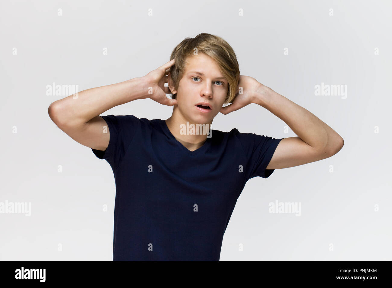 Young man wearing black t-shirt with surprised expression on face against white background Stock Photo