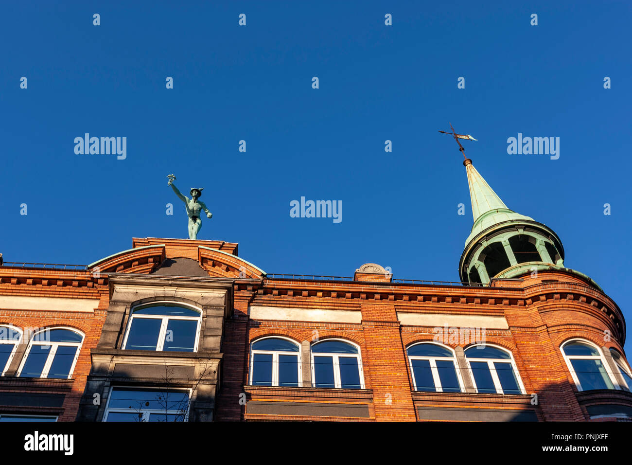 Mercury statue hangs out on the rooftop of a building in Købmagergade Copenhagen, Denmark Stock Photo