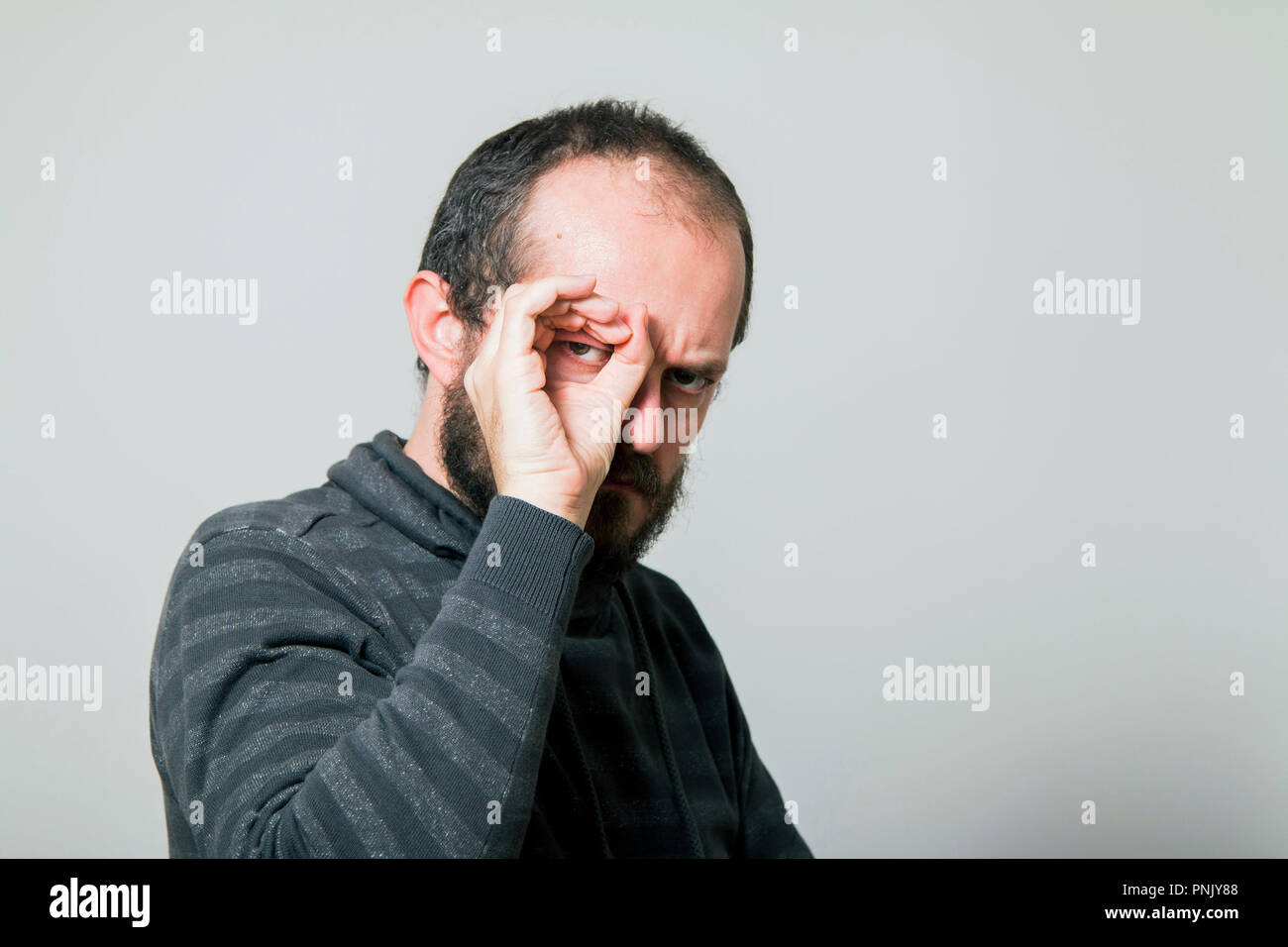 Shocked man looking through hands, making binoculars Stock Photo
