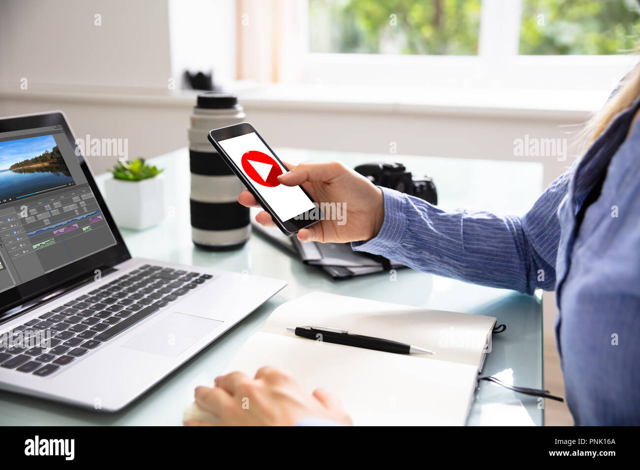 Female Editor Using Cellphone With Play Icon On Screen Stock Photo