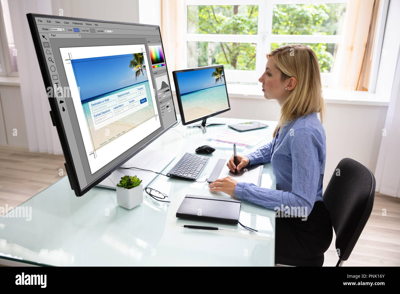 Side View Of A Young Female Designer Using Graphic Tablet While Working On Computer Stock Photo
