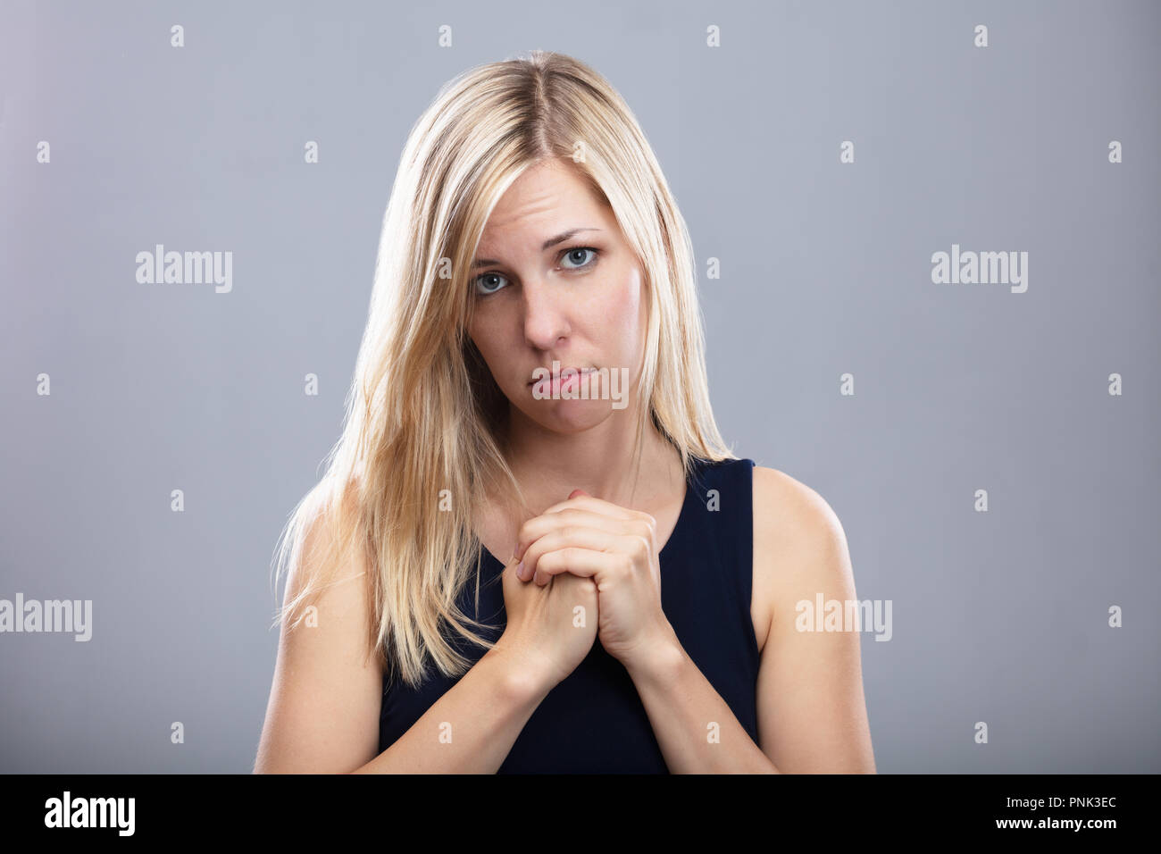 Portrait Of A Sad Young Woman On Grey Background Stock Photo