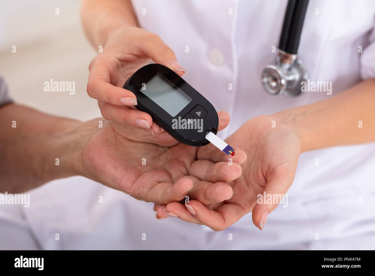 Female Doctor's Hand Measuring Patient's Blood Sugar Level With Glucometer Stock Photo
