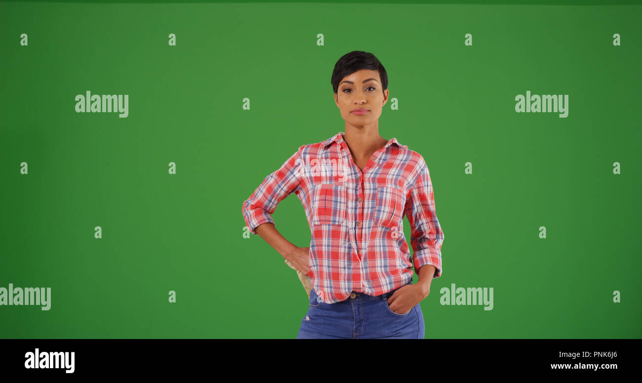 Young black woman in flannel shirt posing confidently on green screen Stock Photo