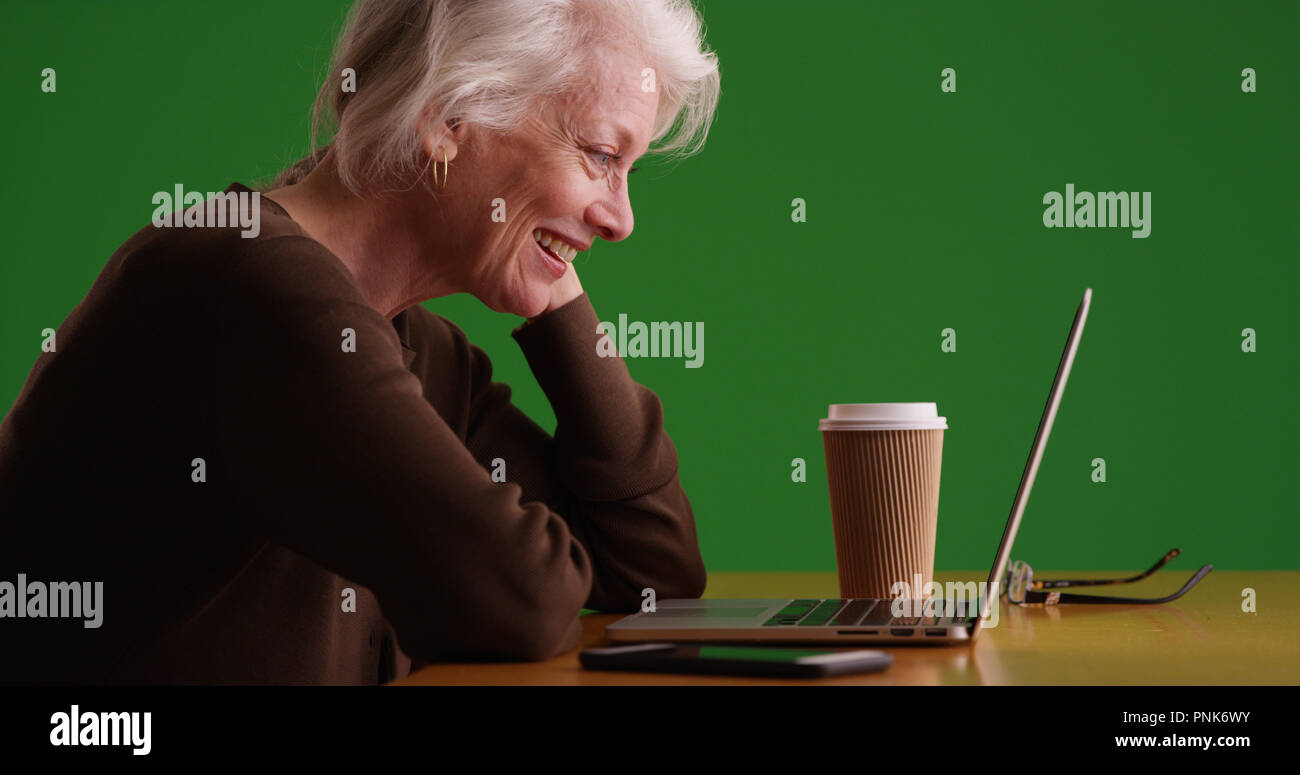 Profile of cheerful mature woman watching funny video on laptop on green  screen Stock Photo - Alamy