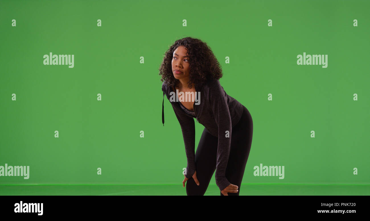 Young black woman runner taking break during workout on green screen Stock Photo