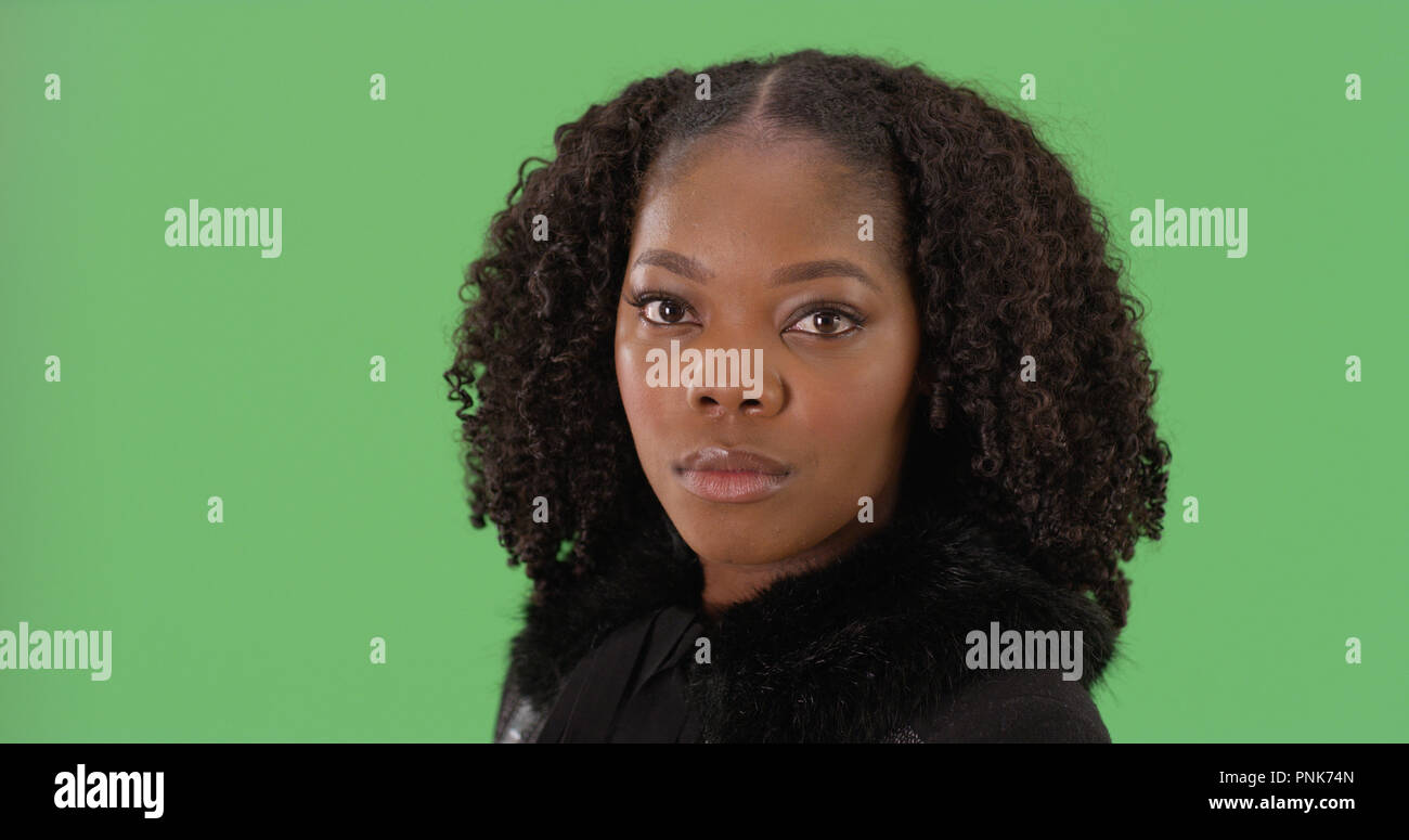 Portrait of stylish African American woman looking at camera on green ...
