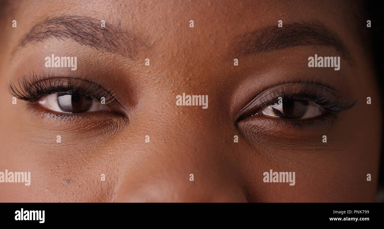 Close up of black female's beautiful eyes looking at camera on green