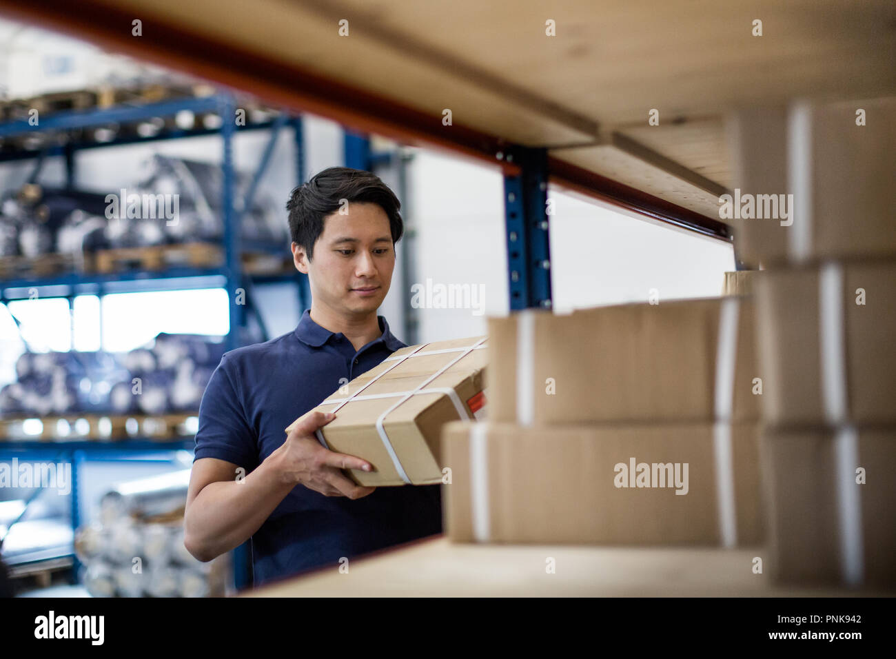 Male picking up box from shelf in distribution warehouse Stock Photo