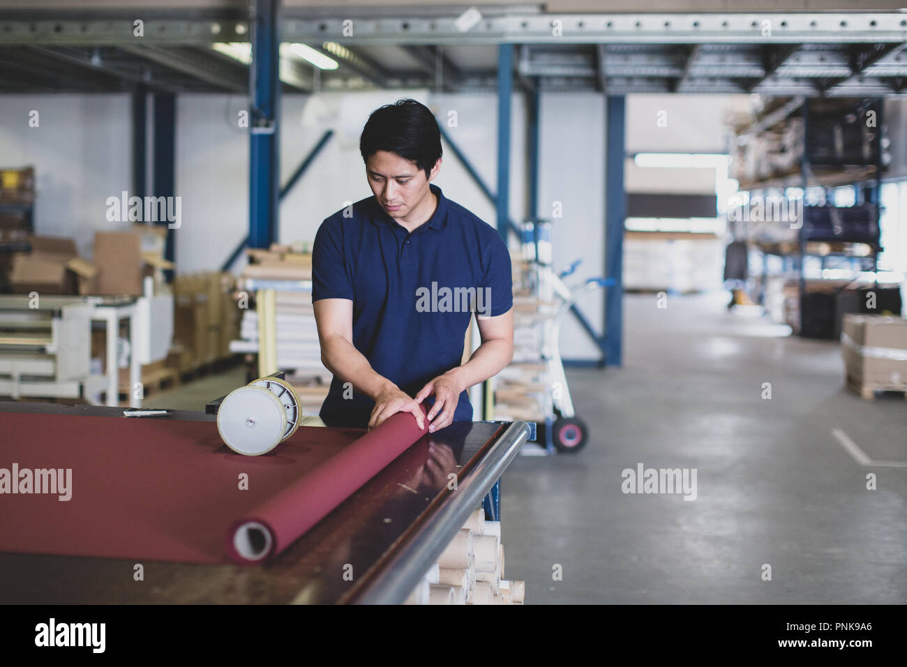 Male cutting fabric in a manufacturing warehouse Stock Photo