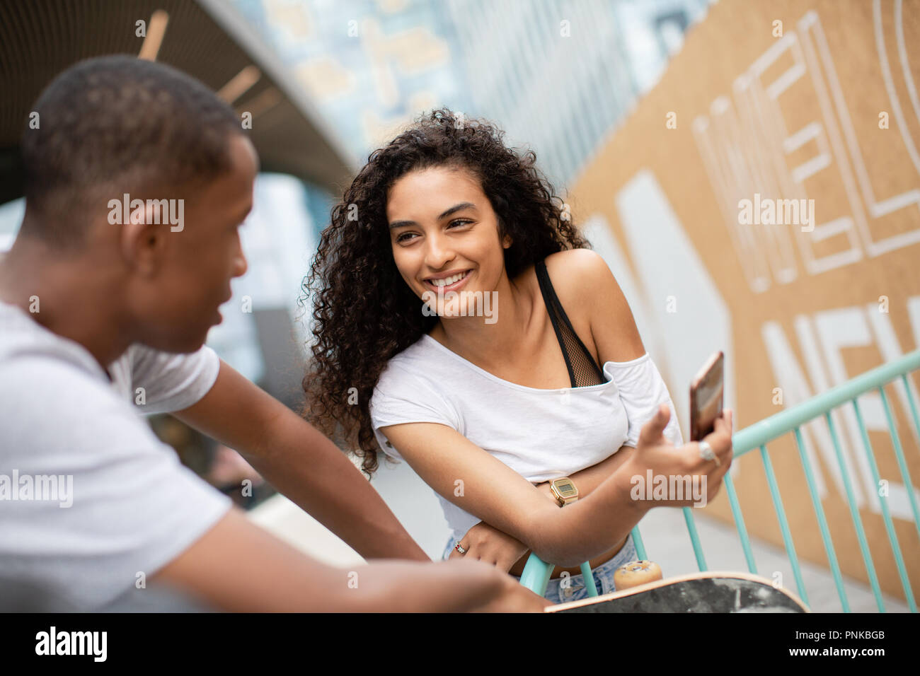 Teenagers socialising outdoors in city with smartphone Stock Photo