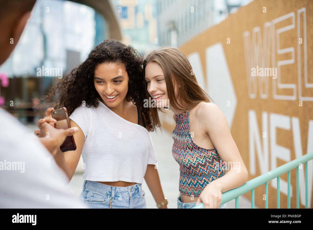 Teenagers socialising outdoors in city looking at smartphone Stock Photo