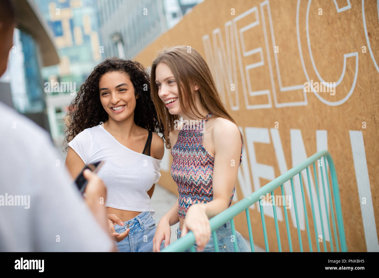 Teenagers socialising outdoors in city with smartphone Stock Photo
