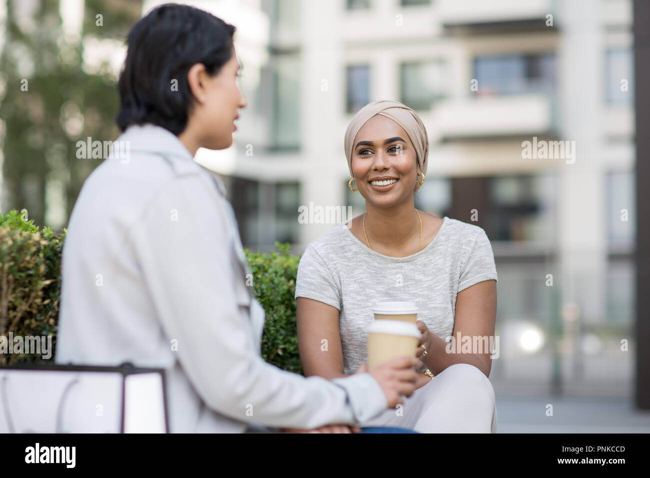 Female Muslim friends having coffee together outdoors Stock Photo