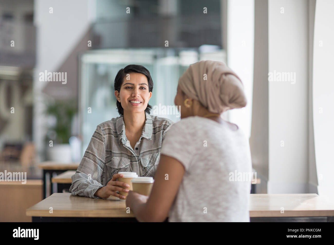 Female Muslim co-workers having coffee together Stock Photo