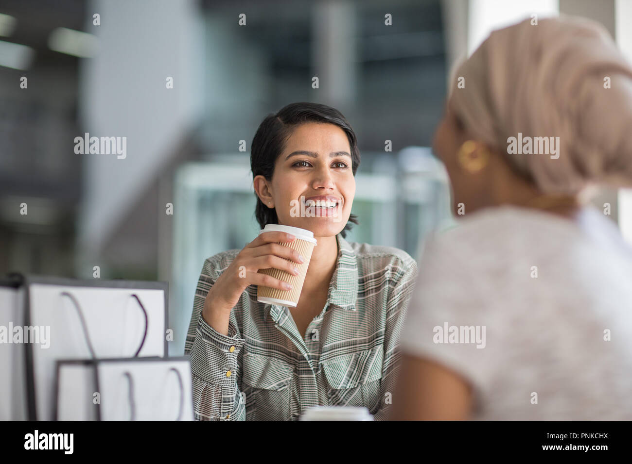 Female Muslim friends having coffee together in a shopping mall Stock Photo