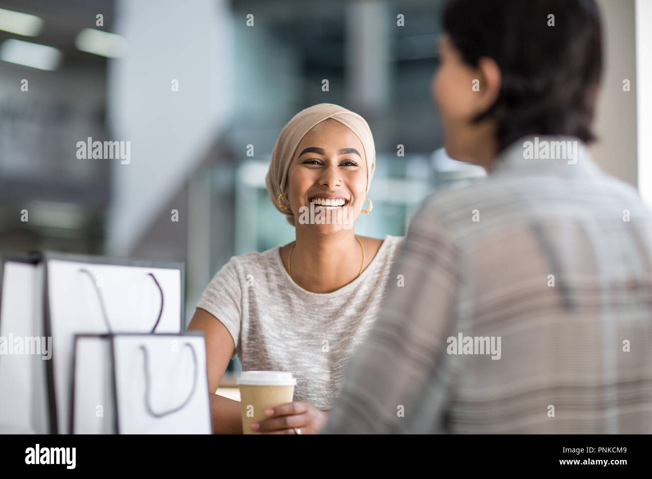 Female Muslim friends having coffee together in a shopping mall Stock Photo
