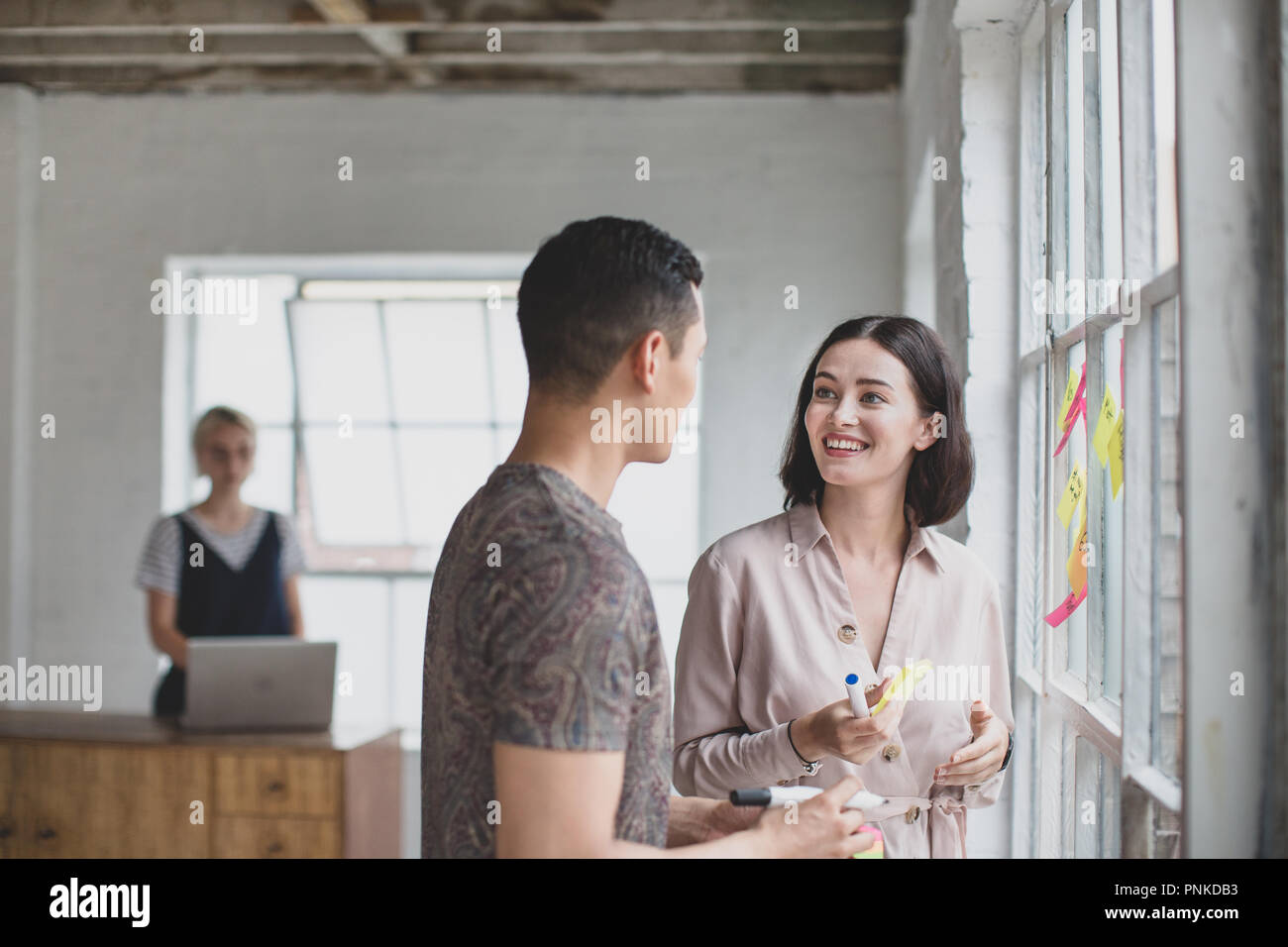 Young adults brainstorming in a creative office with adhesive notes Stock Photo