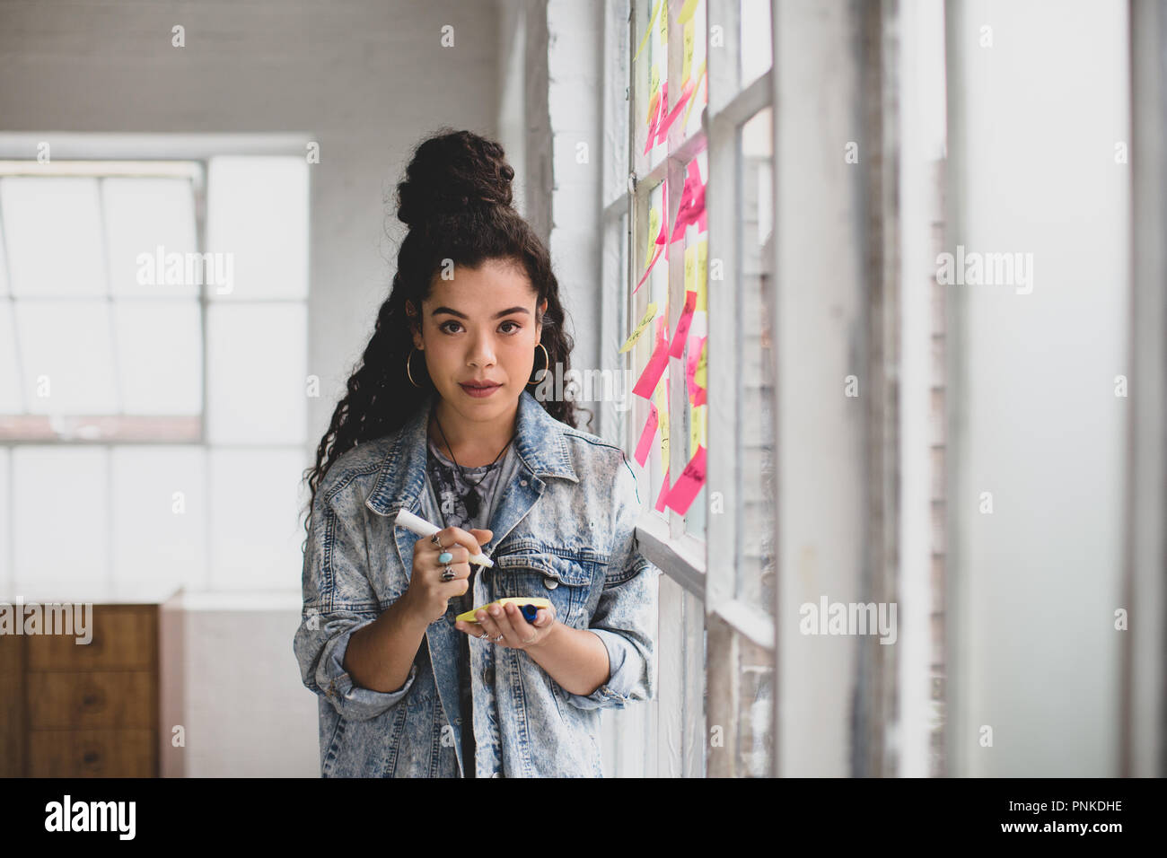 Portrait of young adult female brainstorming in a creative office with adhesive notes Stock Photo
