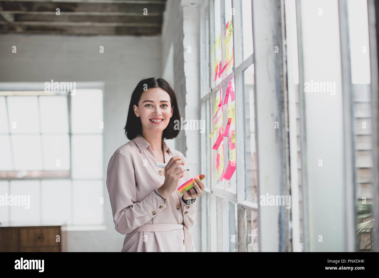 Portrait of young adult female brainstorming in a creative office with adhesive notes Stock Photo