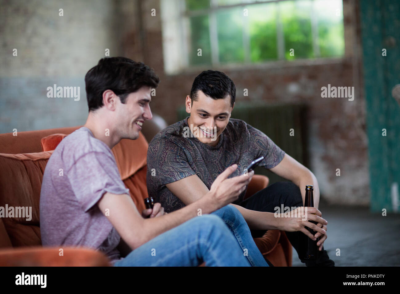 Millennials using smartphones relaxing on sofa Stock Photo