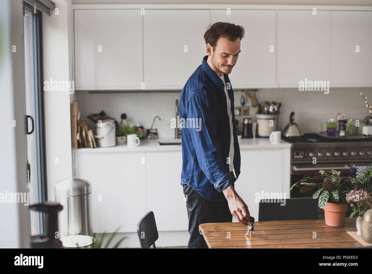 Adult male picking up keys from kitchen table Stock Photo