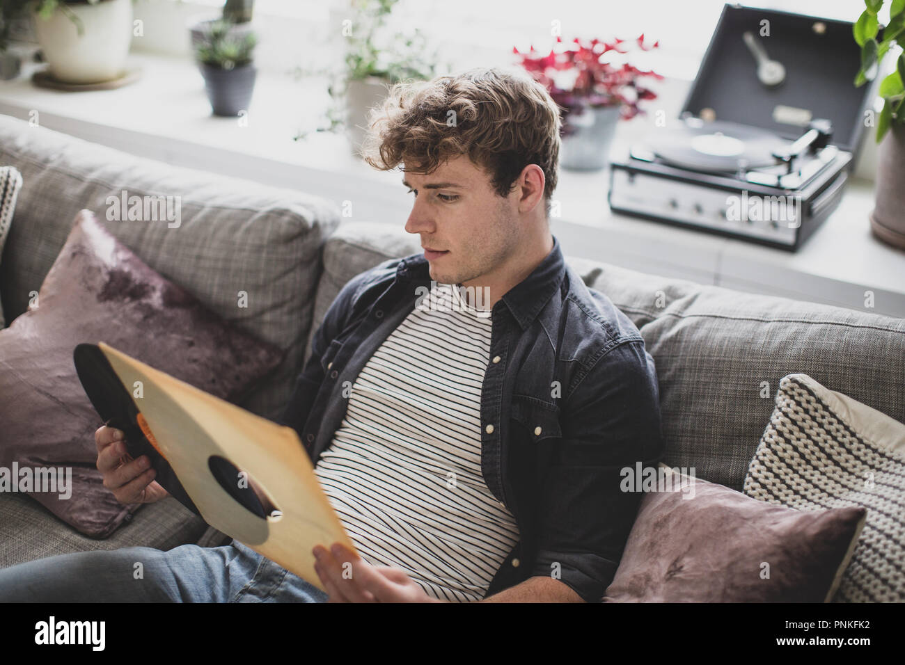 Young adult male looking at vinyl record Stock Photo
