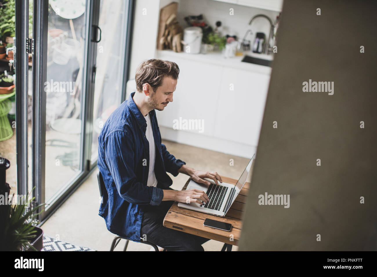 High angle shot of adult male working from home in kitchen Stock Photo