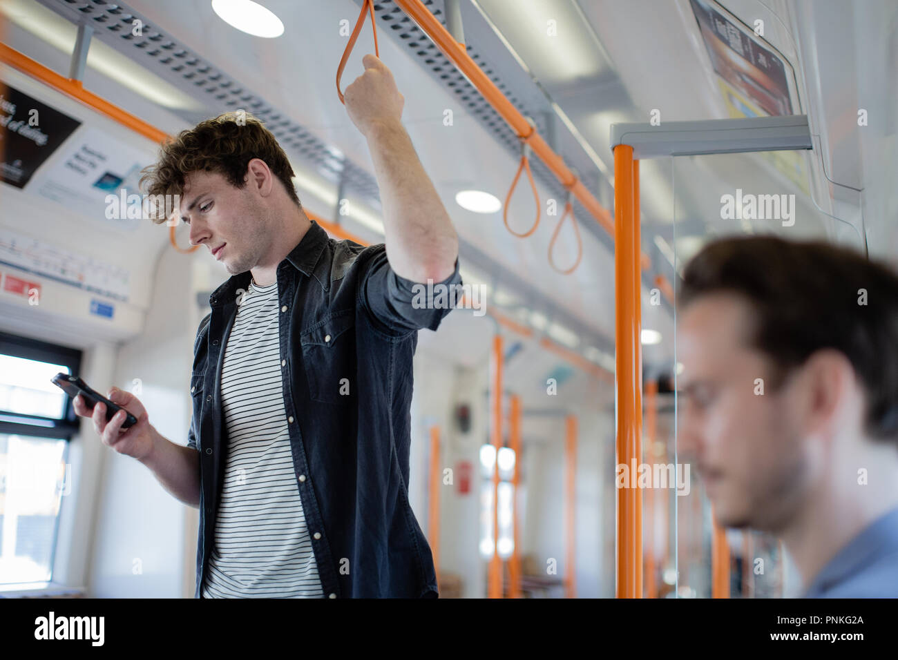 Commuter using smartphone on train Stock Photo