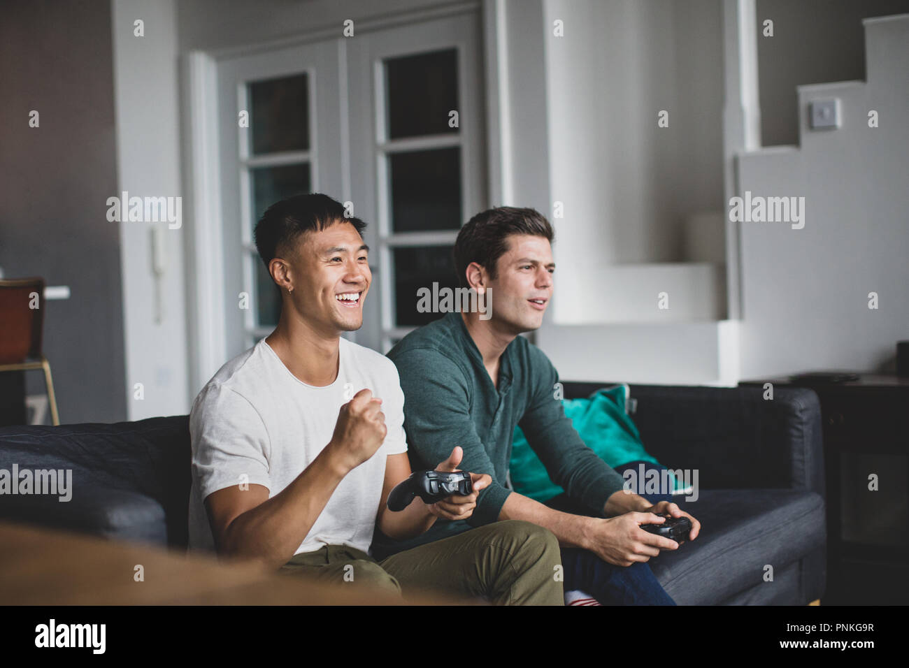 Male friends playing on a games console Stock Photo